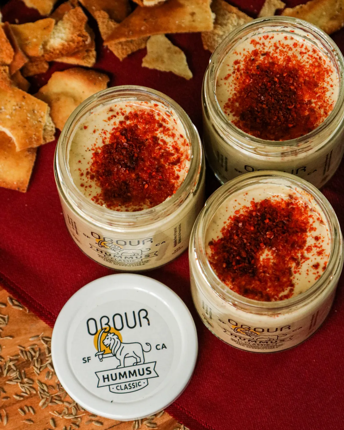 Open jars of Classic hummus topped with Aleppo chile, with pita chips